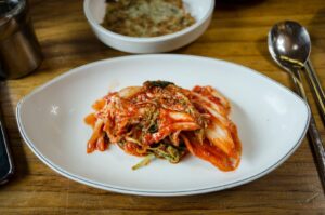 Spicy red fermented cabbage kimchi served on a white plate