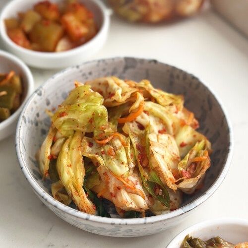 Bowl of colorful cabbage kimchi with vegetables on a table