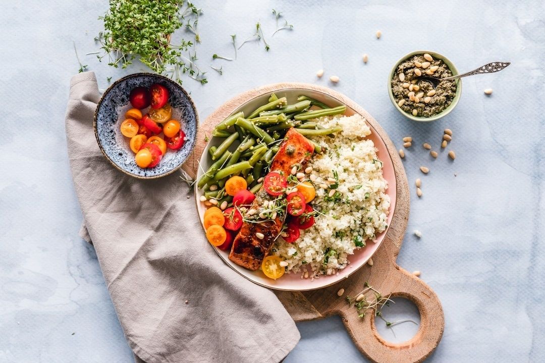 Colorful lunch bowl with salmon, green beans, tomatoes, and grains