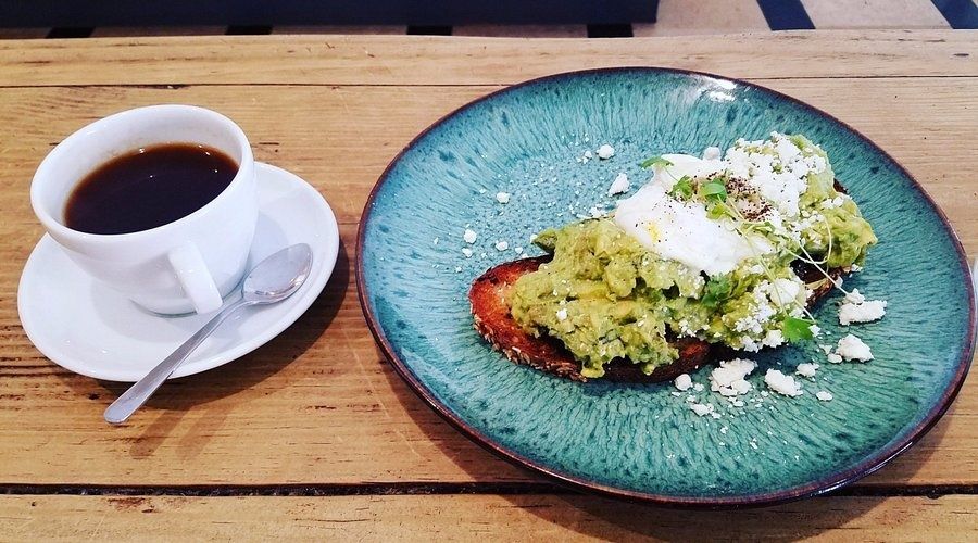 Avocado toast with poached egg and coffee on a cafe table