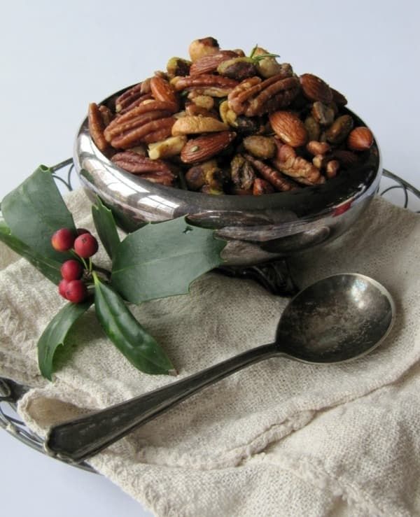Bowl of mixed roasted nuts with holly leaves and a spoon